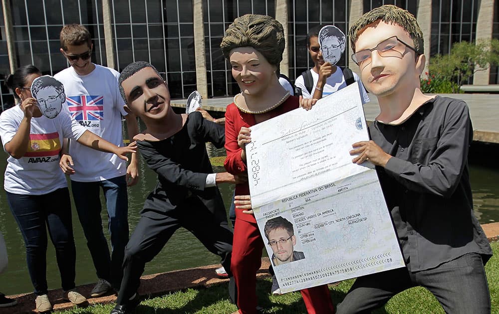 Activists wearing masks of former NSA analyst Edward Snowden, right, Brazil`s President Dilma Rousseff, center, and President Barack Obama perform with an oversized passport outside the foreign ministry to demand Snowden be granted asylum in Brasilia, Brazil.