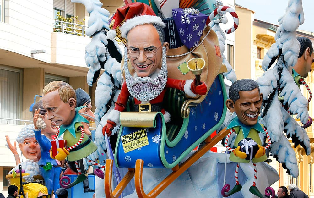 A float depicting former Premier Enrico Letta, center, dressed as Santa Klaus on sledge with a sign reading in Italian `Going out of business`, US President Barack Obama, right, and Russian President Vladimir Putin, left, parades at the traditional Viareggio Carnival, in Viareggio.