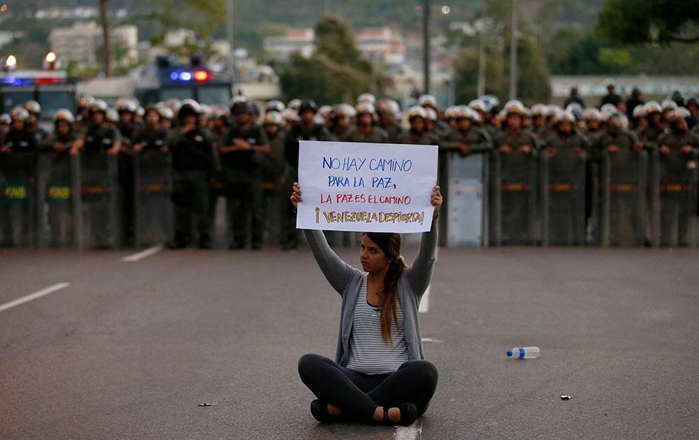 A demonstrator holds up a sign that reads in Spanish `There is no road to peace. Peace is the way. Awake Venezuela` in front of a line of National Bolivarian Guards dressed in riot gear, in Caracas, Venezuela.