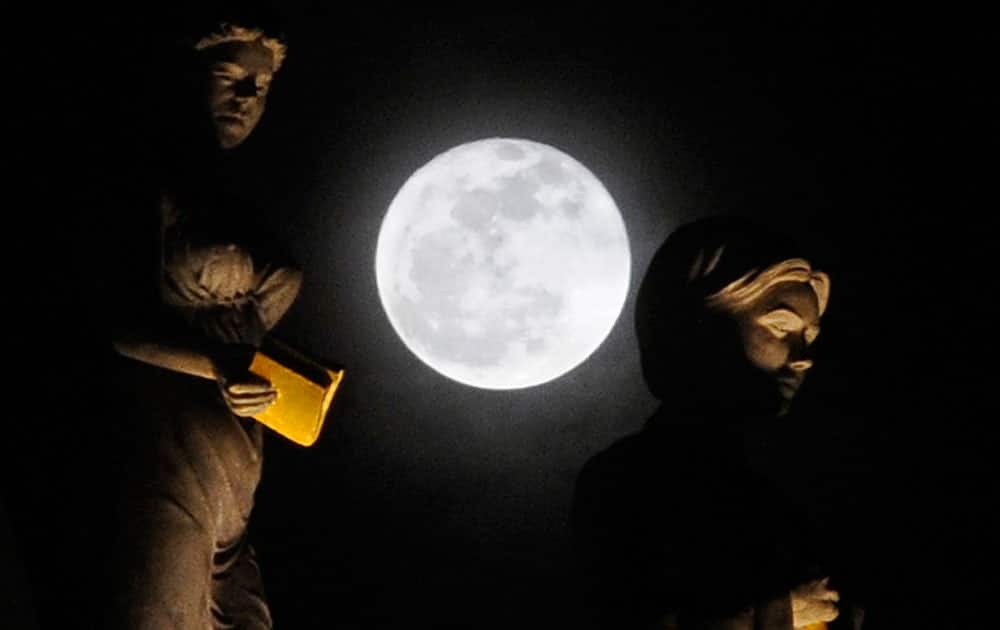 A full moon rises between sculptures atop of the new Macedonian National Theatre, recently rebuilt to resemble the old theatre building destroyed in the earthquake in 1963, in Macedonia’s capital Skopje.