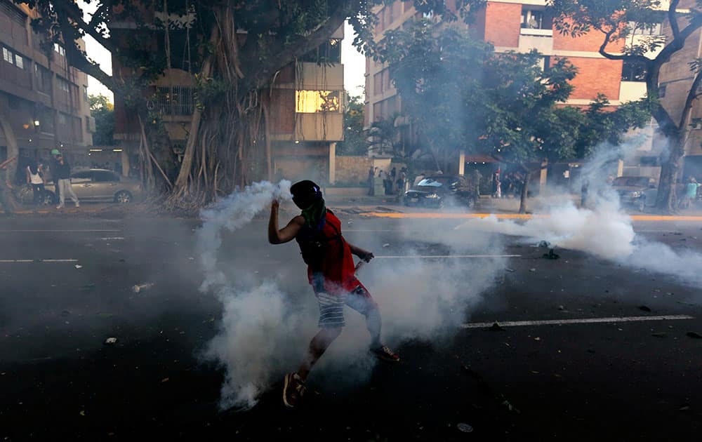 A demonstrator throws back a tear gas canister fired by the National Bolivarian Police(BNP) in Caracas, Venezuela.