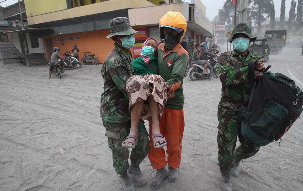 Soldiers and rescuers carry a woman to a truck for evacuation following an eruption of Mount Kelud, in Malang, East Java, Indonesia.