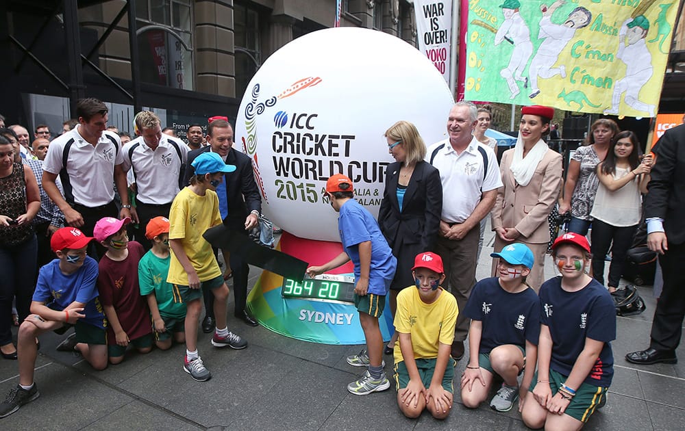 Australian Prime Minister Tony Abbott and two children unveil a countdown clock during a ceremony in Sydney, marking one year to the start of the 2015 ICC World Cup Cricket tournament.