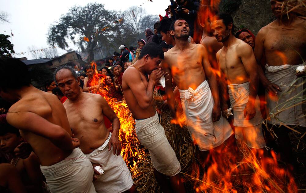 Nepalese Hindus men warm themselves in front of a bonfire before taking a holy dip in the holy Hanumante River, during Madhav Narayan festival in Bhaktapur, Nepal.