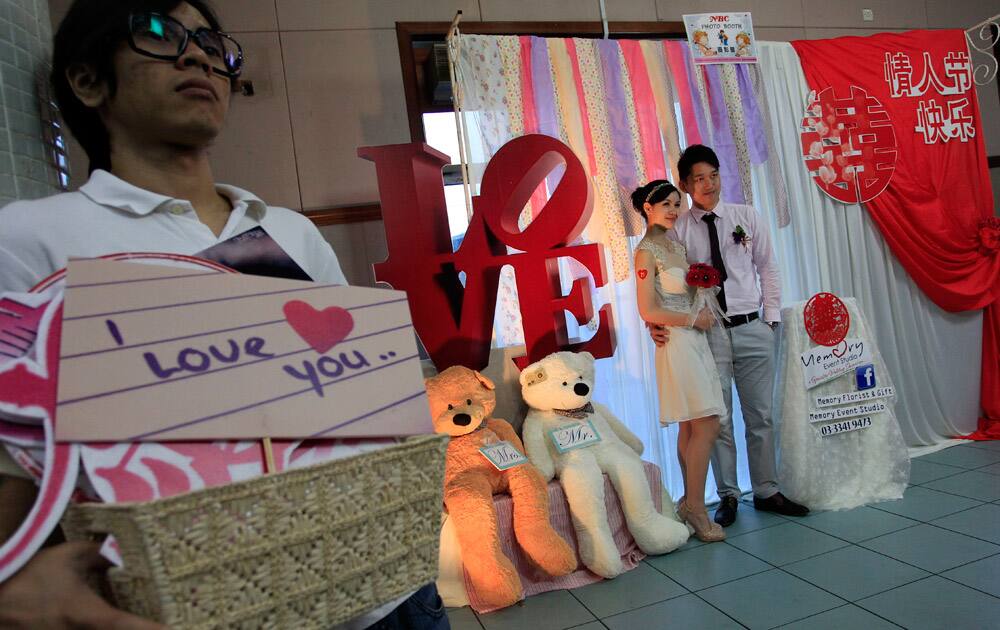 A newly wed couple pose for photos at a photo booth before a mass wedding ceremony on Valentine`s Day and Chap Goh Mei festival, also known as the Oriental Valentine`s Day in Klang, outside Kuala Lumpur, Malaysia.