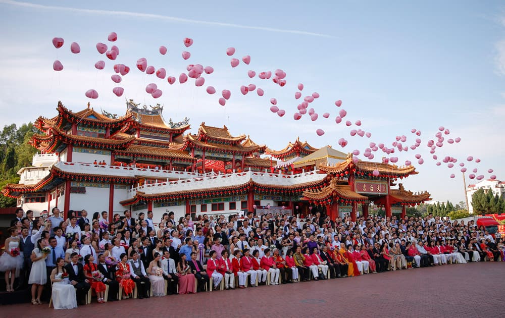 Newly-wed couples and temple leaders release balloons as they pose for a group photo during their mass wedding ceremony on the occasion of the unique date of St. Valentine`s Day and Chinese Valentine`s Day in Kuala Lumpur, Malaysia.