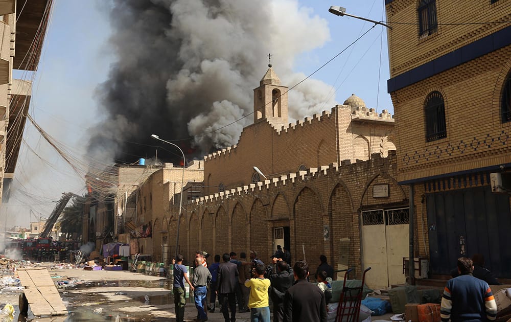 Civilians gather as firefighters try to extinguish fire after a two bombs went off in Baghdad, Iraq.