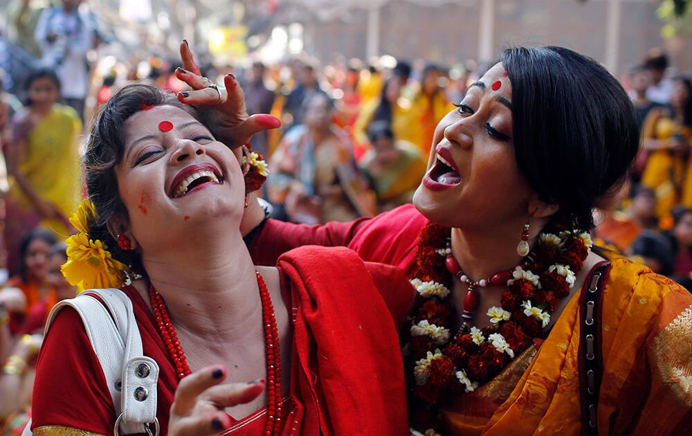 Bangladeshi girls put vermillion powder on each other as they celebrate the arrival of spring on the first day of Falgoon at the Dhaka University campus in Dhaka, Bangladesh.