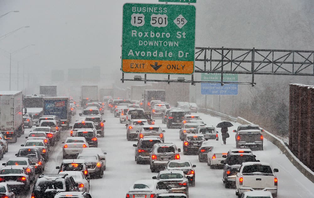 A motorist, right, who abandoned their vehicle, walks through stopped traffic on northbound Interstate 85 during a winter storm in Durham, N.C.