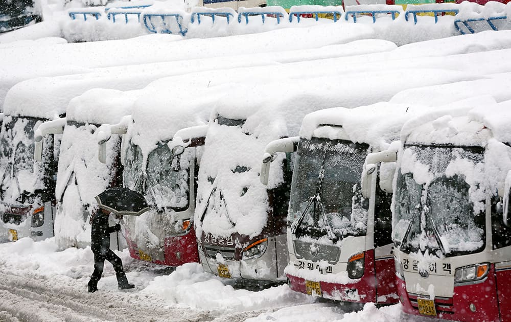 A man walks past snow-covered buses as more than one meter (3.3 feet) of snow fell last week in Gangneung, South Korea.