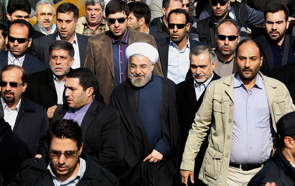 Escorted by his bodyguards, Iranian President Hassan Rouhani, center, attends an annual rally commemorating the anniversary of the 1979 Islamic revolution, in Tehran, Iran.