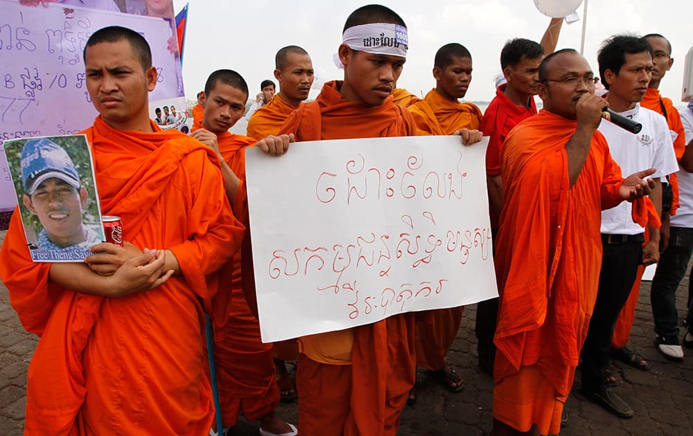 Buddhist monks hold the portrait of a detainee and a banner reading `Free human rights activists, hero workers` during a prayer in a rally calling for the release of the detained anti-government protesters, in front of the Royal Palace in Phnom Penh, Cambodia.