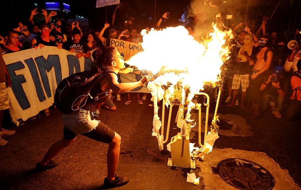 A girl spits fire on a bus turnstile set on a street in protest against the increase on bus fares in Rio de Janeiro, Brazil.