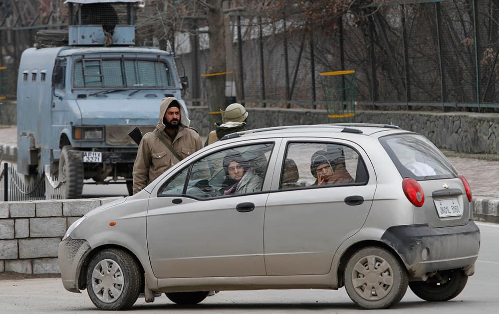 Kashmiri civilians in a car look at their family member talking to policemen after being stopped during a strike in Srinagar.
