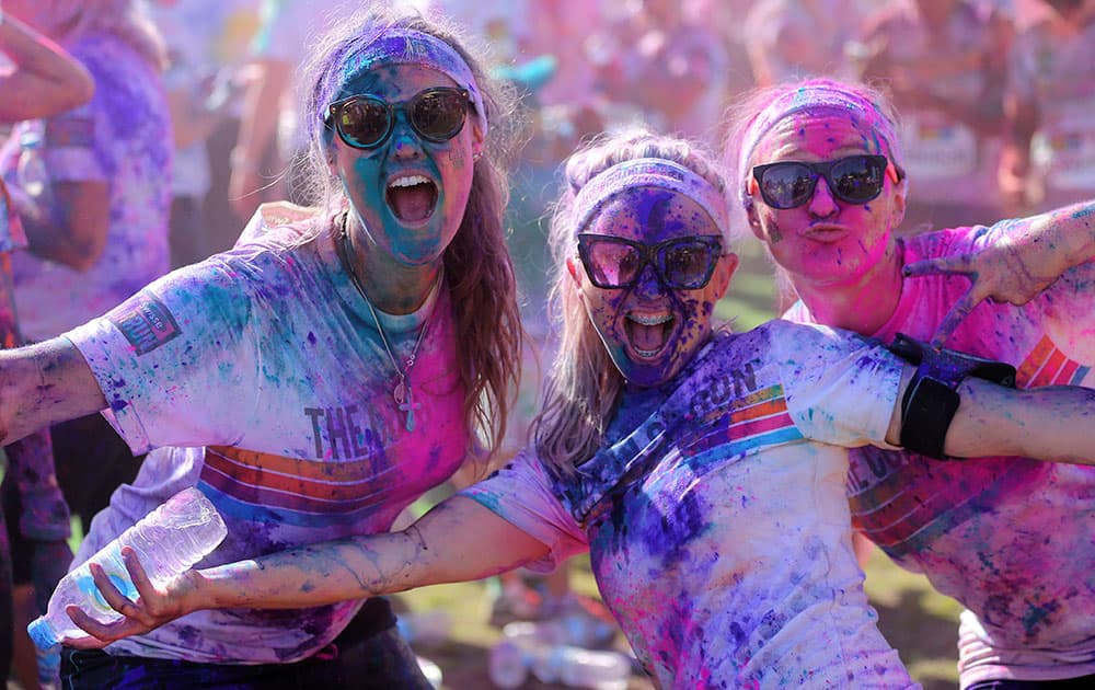 Three girls pose for a photo during a party festival at the Color Run in Sydney, Australia. The Color Run event is a 5 km (3.1 mile) fun run where participants are covered with bright colored powder at each check station and is less about speed and more about enjoying a color crazy day with friends and family.