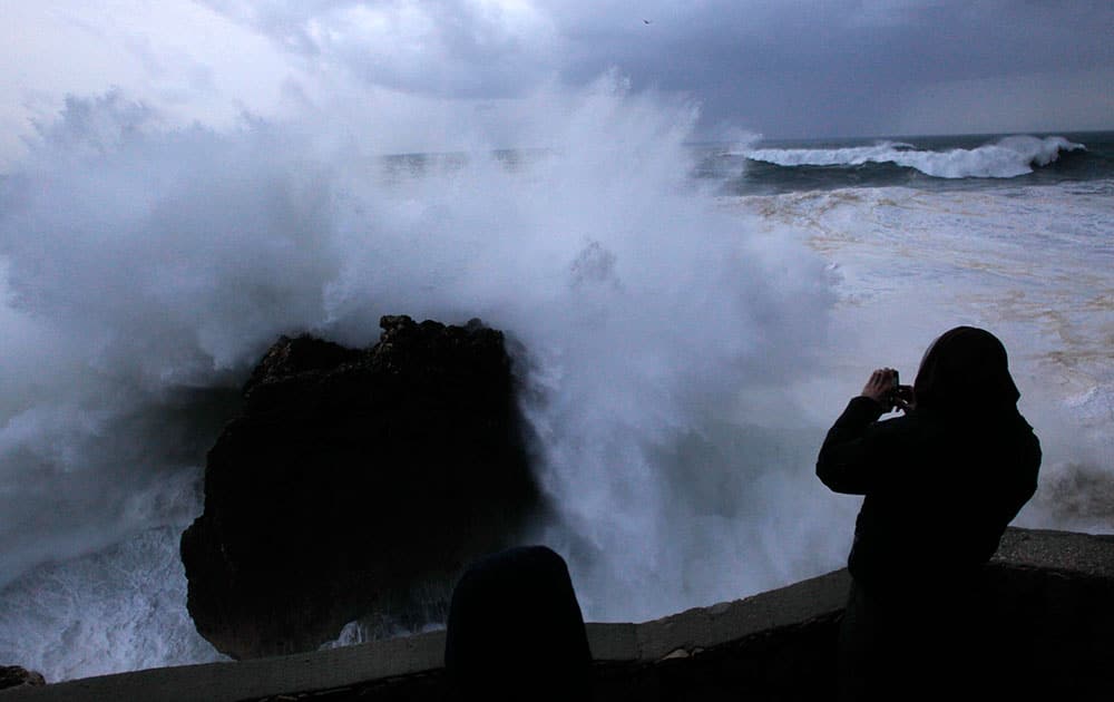 A man takes photographs of huge waves hitting rocks at the Nazare lighthouse, outside the fishing village of Nazare, on the central coast of Portugal.