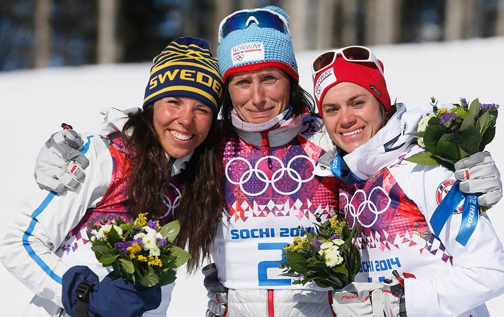 Norway`s gold medal winner Marit Bjoergen is flanked by Sweden`s silver medal winner Charlotte Kalla, left, and Norway`s bronze medal winner Heidi Weng after the flower ceremony for the women`s cross-country 15k skiathlon at the 2014 Winter Olympics, in Krasnaya Polyana, Russia.