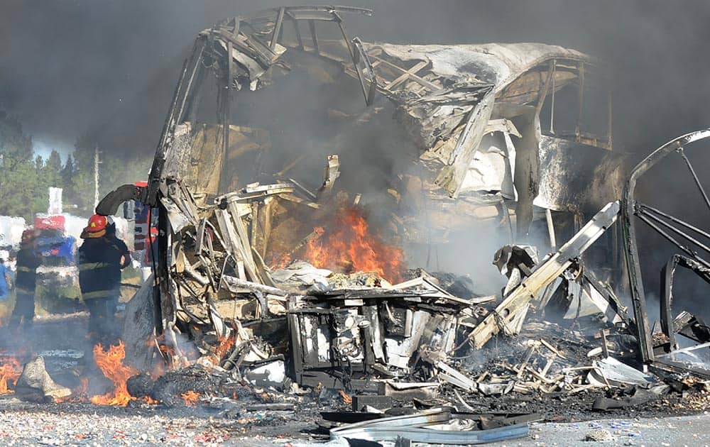 Firefighters put out the fire of a wrecked bus that collided head on with a truck near San Martin, Argentina.