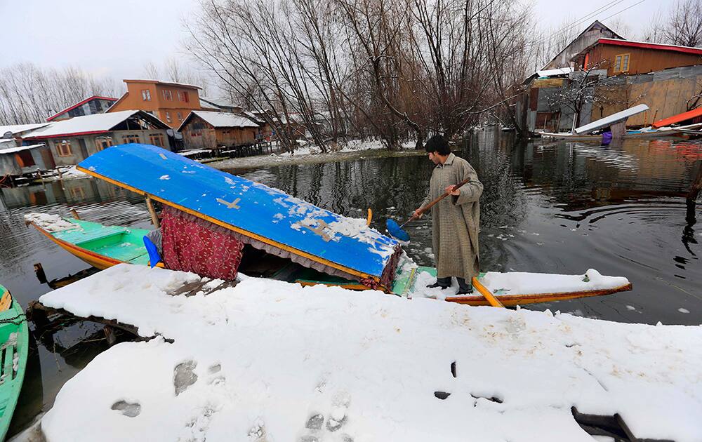 A Kashmiri boatman clears snow from the roof of his shikara, traditional gondola, on the shore of Dal Lake after fresh snowfall in Srinagar.