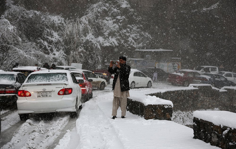 An Afghan man takes a photo on snow-covered Kabul-Jalalabad road on the outskirts of Kabul, Afghanistan. Kabul has been experiencing below freezing weather and snow.
