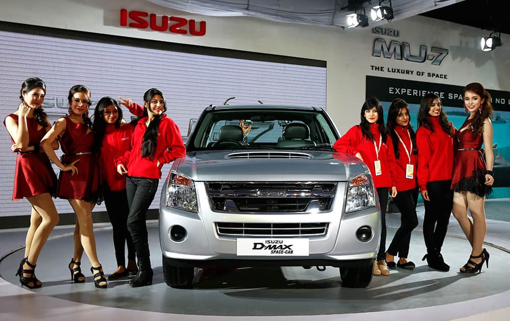 Models and workers pose for photographs with an ISUZU pick up truck called D-Max Space Cab, at the 12th Indian auto Expo in Noida.