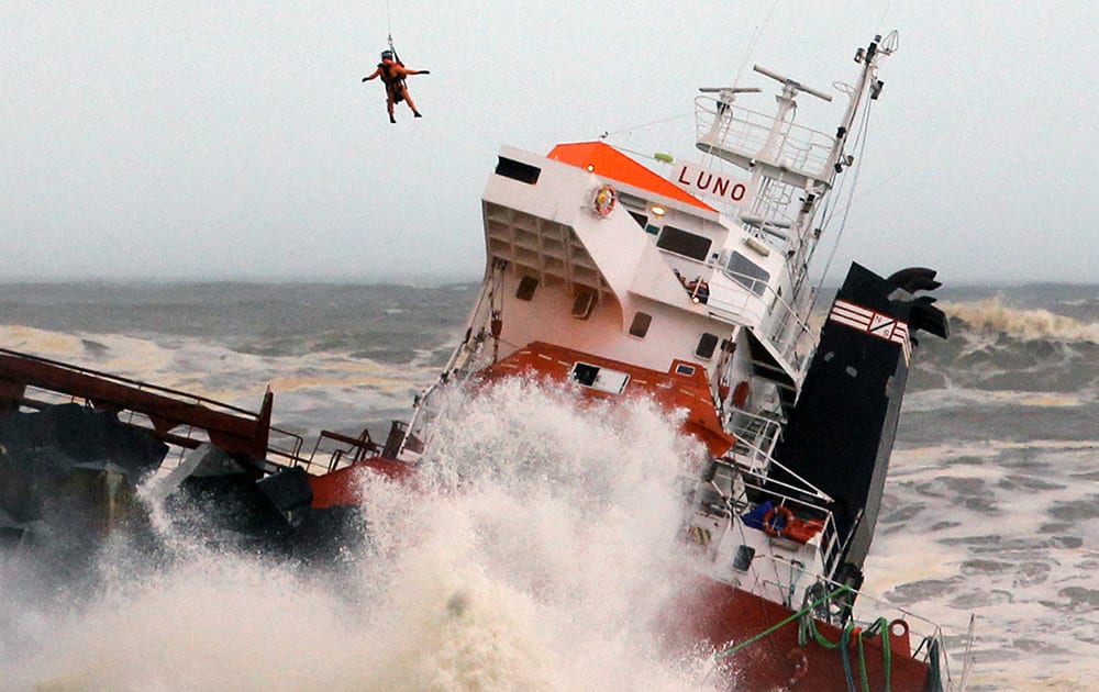 A helicopter lowers a rescue worker toward a Spanish cargo ship the Luno that slammed into a jetty in choppy Atlantic Ocean waters off Anglet, southwestern France.