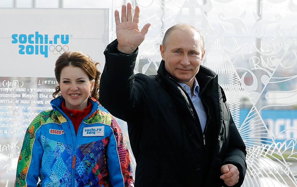 Russian President Vladimir Putin waves after signing his name on a board during the welcome ceremony for Russia`s Olympic team ahead of the 2014 Winter Olympics in Sochi, Russia.