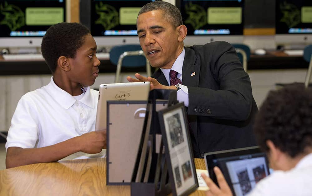 President Barack Obama looks at a student`s iPad project at Buck Lodge Middle School in Adelphi, Md., where he spoke about his ConnetED goal of connecting 99% of students to next generation broadband and wireless technology within five years.