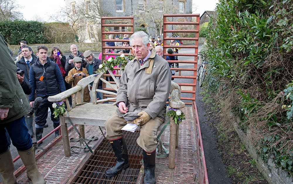 Britain`s Prince Charles sits on a garden bench on a tractor-towed trailer as he travels through the flood-hit community of Muchleney, southwest England.