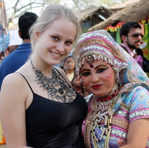 A foreign tourist poses for photograph with a Braj artist during 28th Surajkund International Crafts Mela in Faridabad .