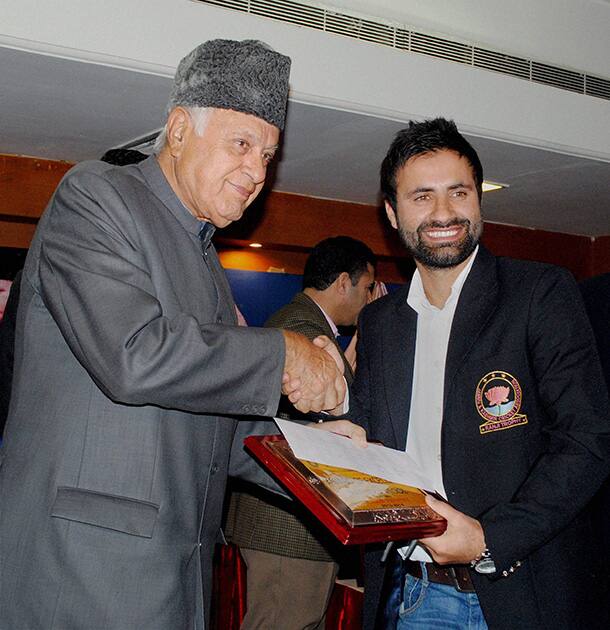 Union Minister for New and Renewable Energy and President of Jammu & Kashmir Cricket Association (JKCA) Farooq Abdullah (L) felicitates Jammu and Kashmir captain Parvez Rasool during a welcome party for Ranji trophy team in Jammu.