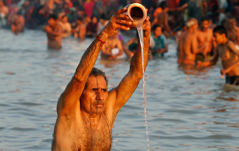 A Hindu devotee offers prayers to Sun God at Sangam, confluence of Hindu holy rivers of Ganges, Yamuna and the mythical Saraswati, for a ritual dip, on the auspicious occasion of “Basant Panchami” at the annual traditional fair of Magh Mela in Allahabad.