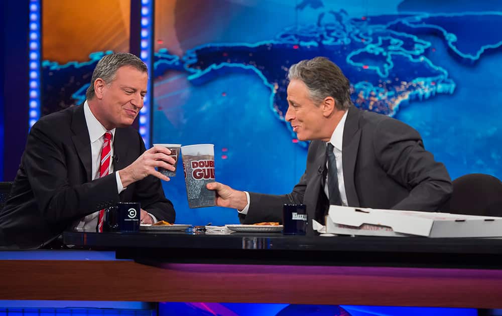 New York Mayor Bill de Blasio, left, shares pizza and soda with host Jon Stewart on Comedy Central`s `The Daily Show` 2014 in New York.