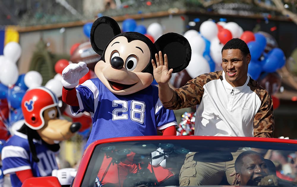 The 2014 Super Bowl MVP Malcolm Smith a Seattle Seahawks linebacker, waves to spectators as he rides in a parade at Walt Disney World with Mickey Mouse in Lake Buena Vista, Fla.