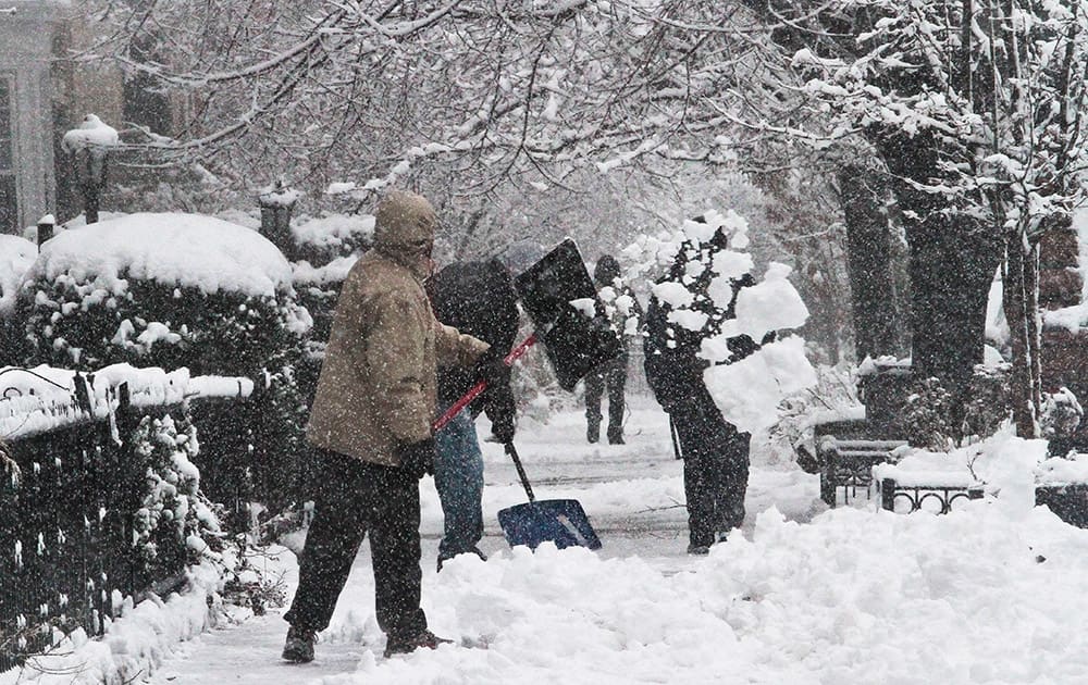 Shovelers remove snow from a sidewalk in Brooklyn`s Flatbush neighborhood in New York. Nearly 2,000 flights and 1,500 canceled flights have been reported nationwide in cities including Philadelphia, Newark, N.J., and New York.