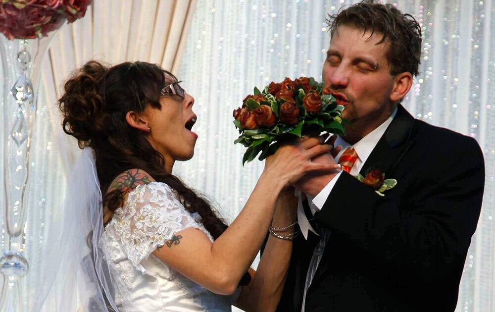 Craig Rouch takes a bite out of his bride April`s bacon bouquet before their wedding during the Blue Ribbon Bacon Festival at the Iowa State Fairgrounds in Des Moines, Iowa.