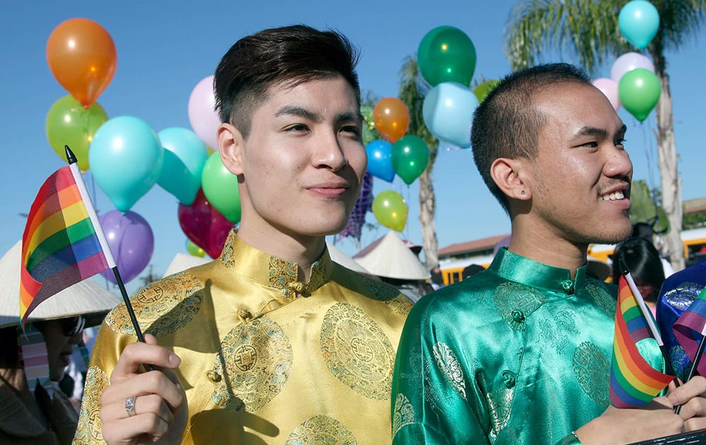 Timothy Truong, left, and Peterson Pham march with others in the Lunar New Year parade, as part of the gay and lesbian group Viet Rainbow of Orange County, in Westminster, Calif.