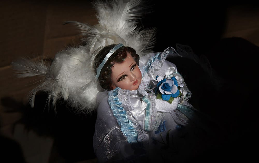 A figure of baby Jesus dressed as an angel is held by its owner at a stand that sells clothes for baby Jesus dolls in Mexico City.