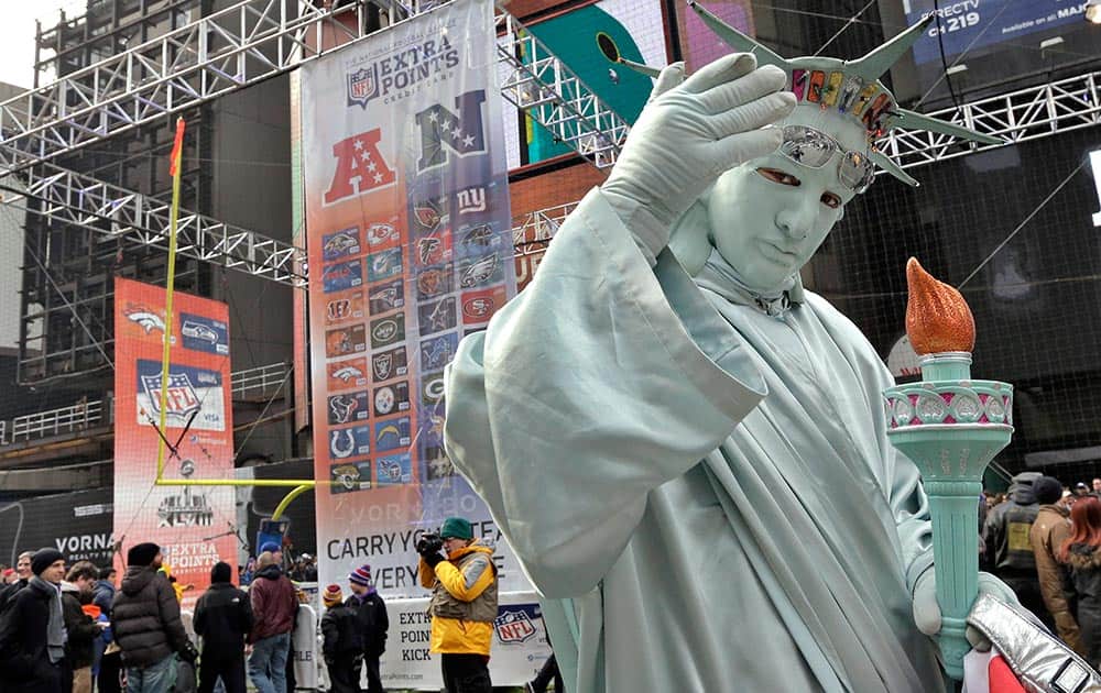 A man dressed as the Statue of Liberty poses for photos with football fans along Super Bowl Boulevard, in New York.