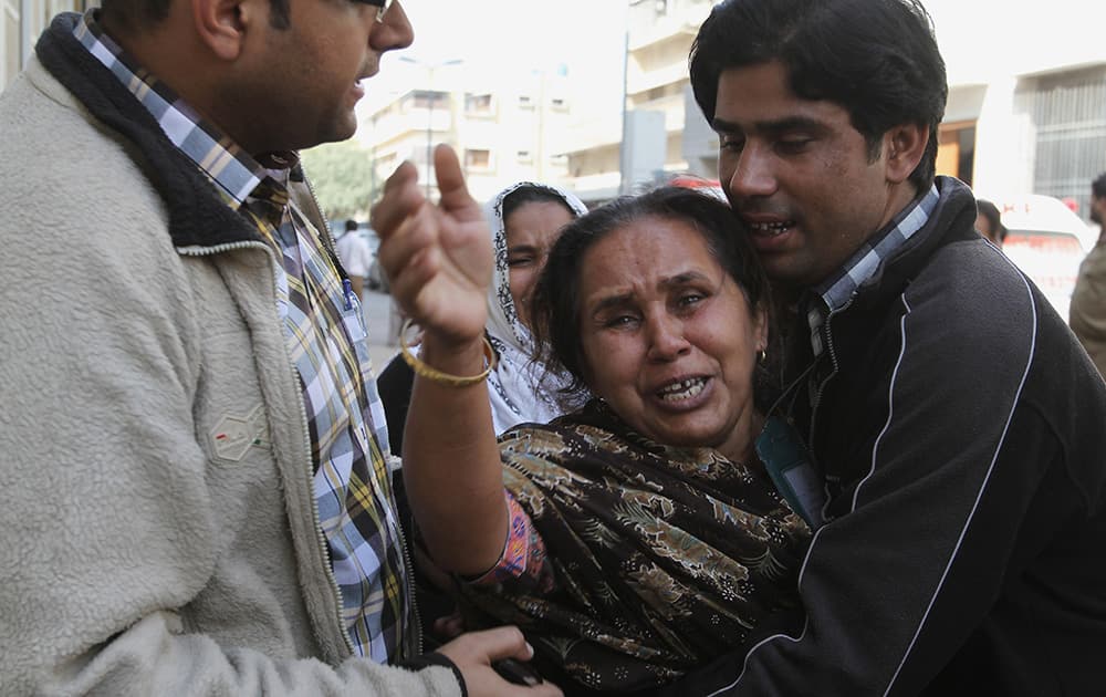 People comfort a woman who said she lost her husband in an attack in Karachi, Pakistan. Police said several members of the country`s security forces have been killed in separate attacks in the southern city of Karachi.