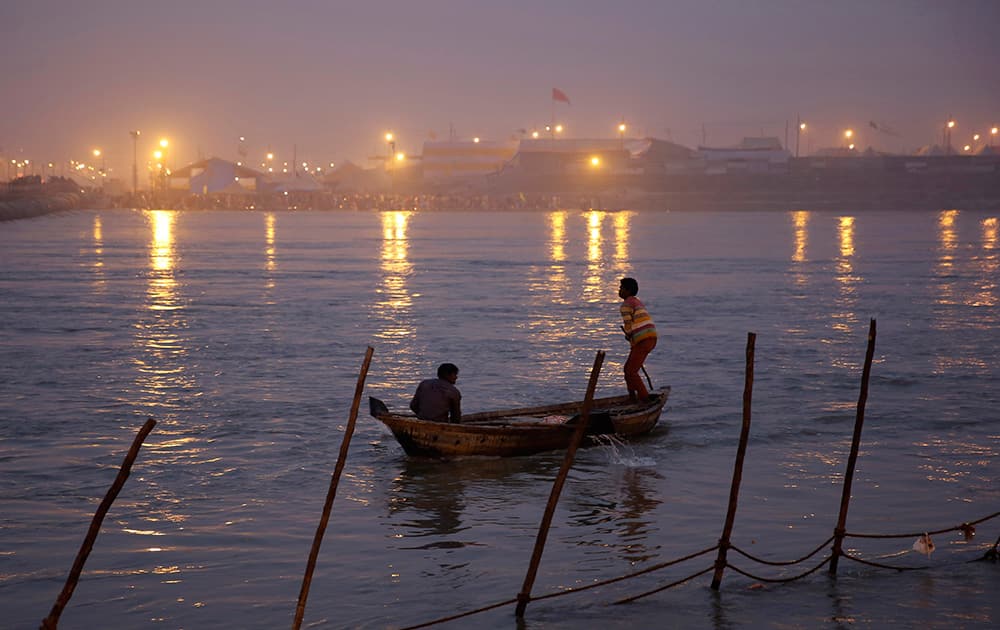 A man rows a boat at Sangam, the confluence of the Rivers Ganges and the Yamuna during the annual traditional fair