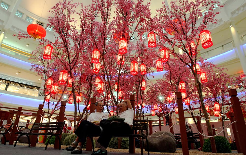 Two shopper resting behind the Chinese plum blossoms trees decoration in Kuala Lumpur, Malaysia. The Lunar New Year begins on Jan. 31 and marks the start of the Year of the Horse, according to the Chinese zodiac.