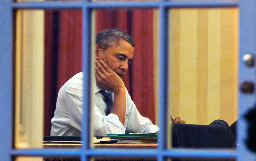 President Barack Obama works at his desk in the Oval Office of the White House in Washington, ahead of Tuesday night`s State of the Union speech.