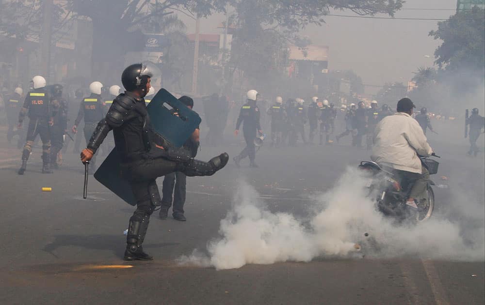 A Cambodian riot police officer avoids a gas grenade as police fire grenades to disperse protesters led by Cambodia`s most prominent human rights defender Mam Sonando to demand the government to allow him to open a new television channel in front of the Ministry of Information in Phnom Penh, Cambodia.