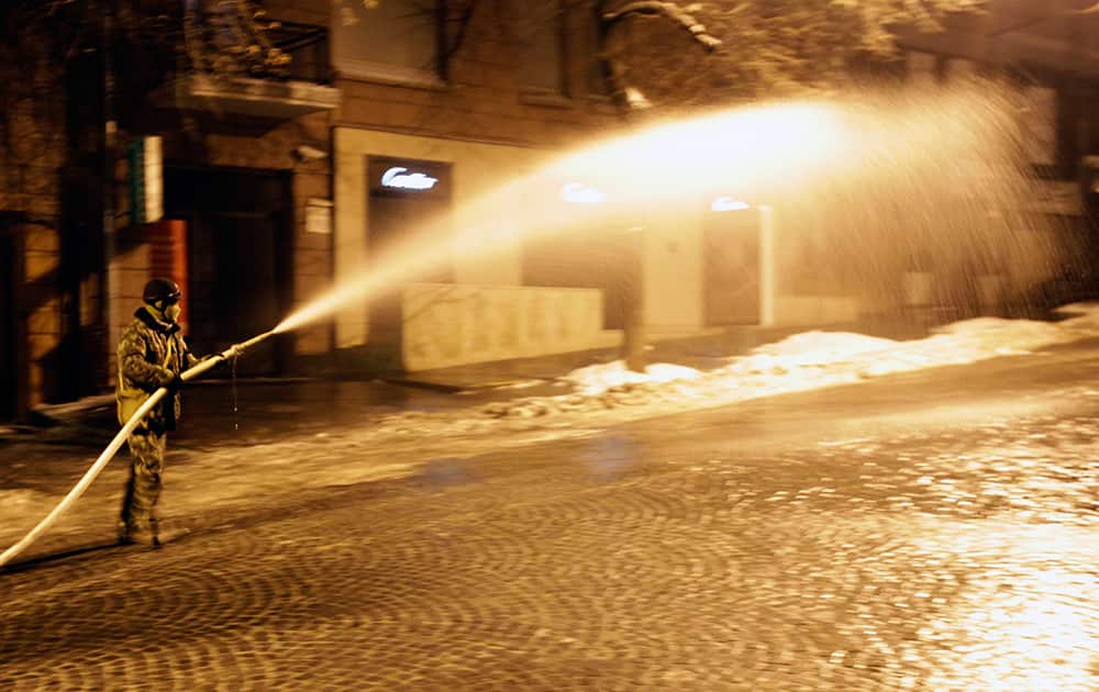 A protester sprays water on a street in the hopes it will freeze, thus making it inaccessible to police in front of the Justice Ministry in Kiev, Ukraine.