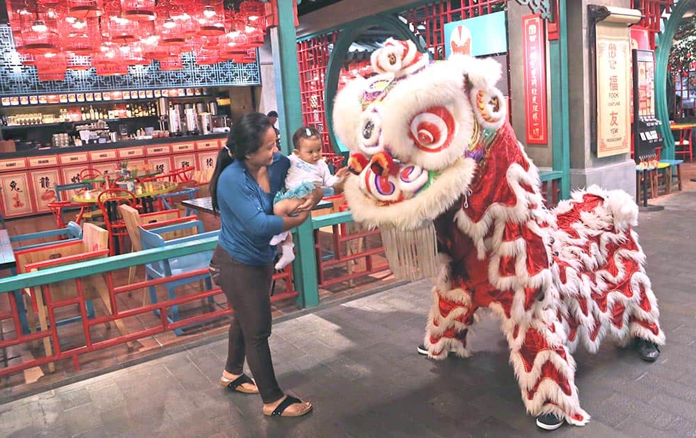 An Indonesian ethnic Chinese with a child watches a dragon dance during Chinese New Year celebrations at a shopping mall in Jakarta.
