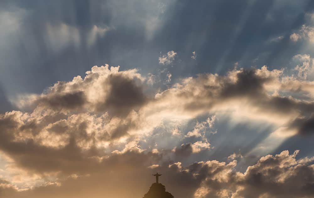 Christ the Redeemer statue is silhouetted against an early evening sky as the sun sets in Rio de Janeiro, Brazil.