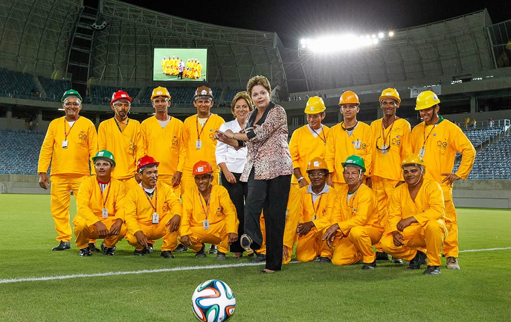 President Dilma Rousseff kicks a soccer ball as she poses for a photo with workers during the inauguration of the Arena das Dunas soccer stadium in Natal, Brazil.