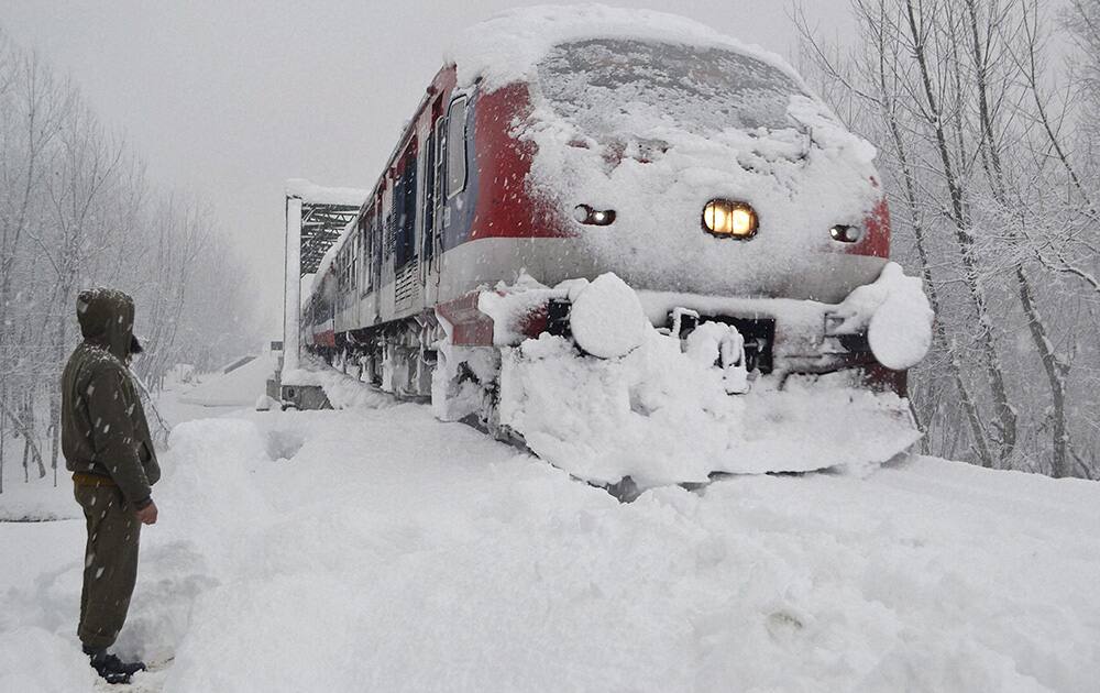 A railway policeman stands guard as a train runs on its tracks amid heavy snowfall in South Kashmir’s Anantnag district on Wednesday. Most places in J&K recorded sub-zero temperatures.