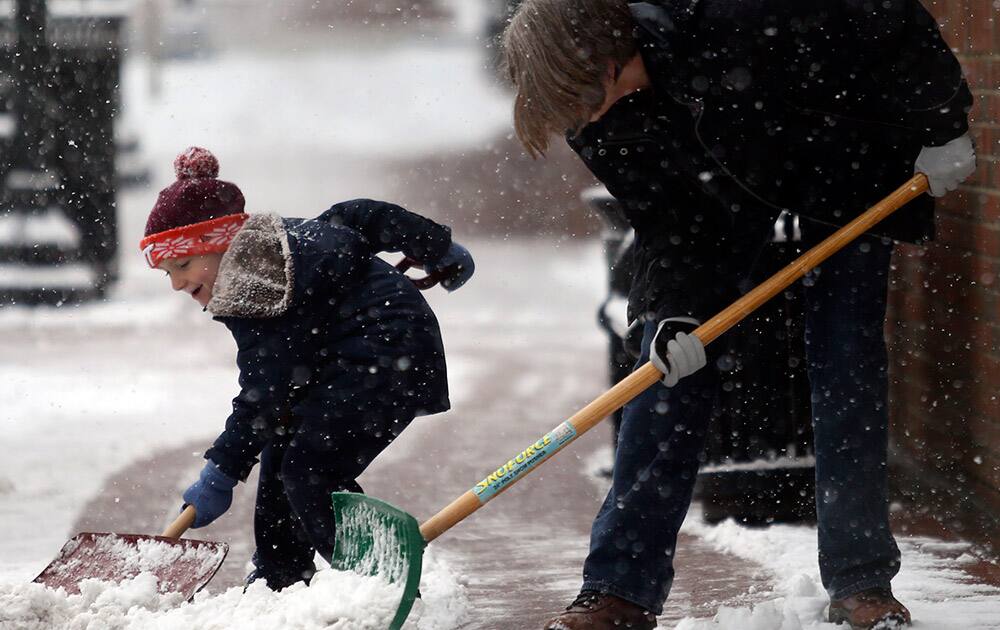 Riley Lopez, 5, left, shovels snow next to his grandmother Bobbie Lopez, right, in downtown Blacksburg, Va.